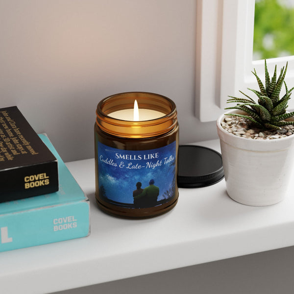 Candle in an amber jar with a label on a shelf next to books and a plant