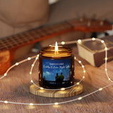 Candle with a label featuring a couple under the moonlight, surrounded by string lights on a wooden surface.