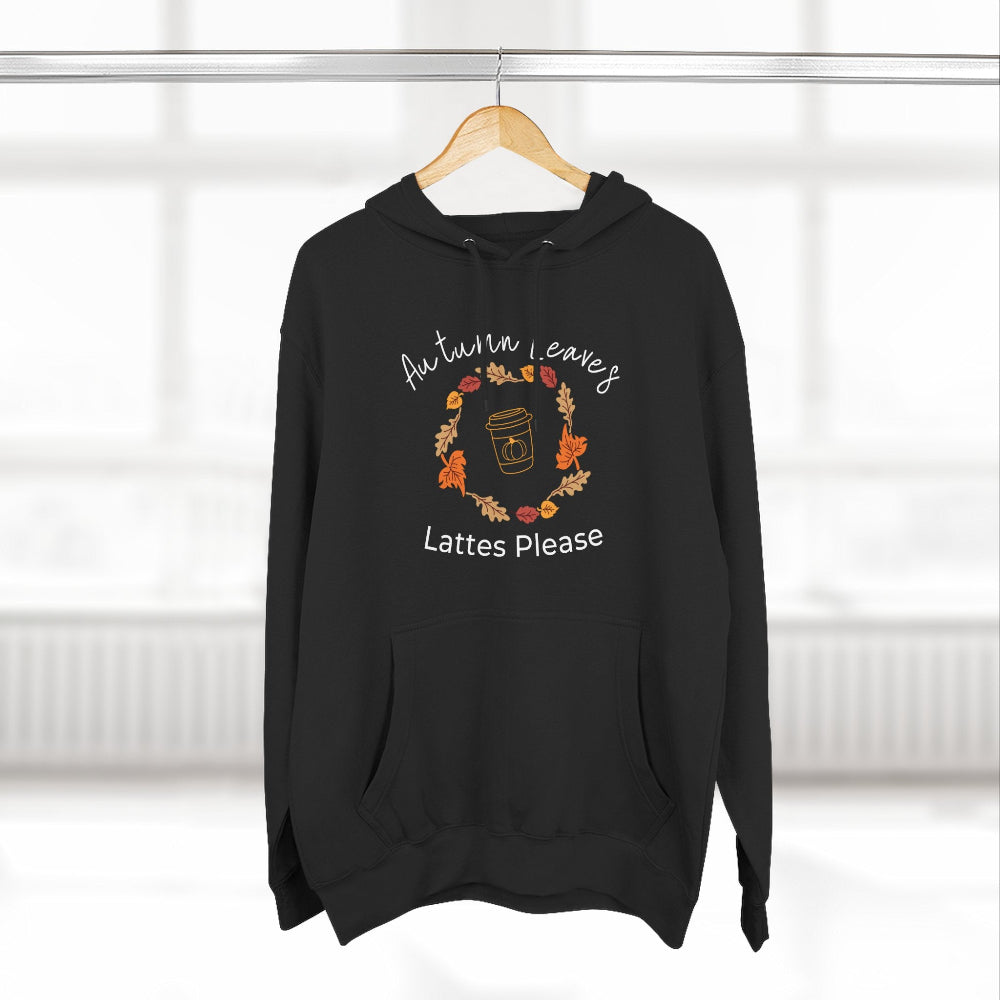 Black hoodie with autumn leaves and lattes design on a hanger against a white background