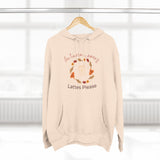 Beige hoodie with autumn leaves and lattes text on a hanger against a white background