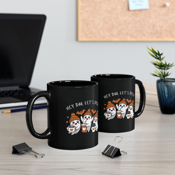 Two black mugs with Halloween-themed design on a desk with office items.