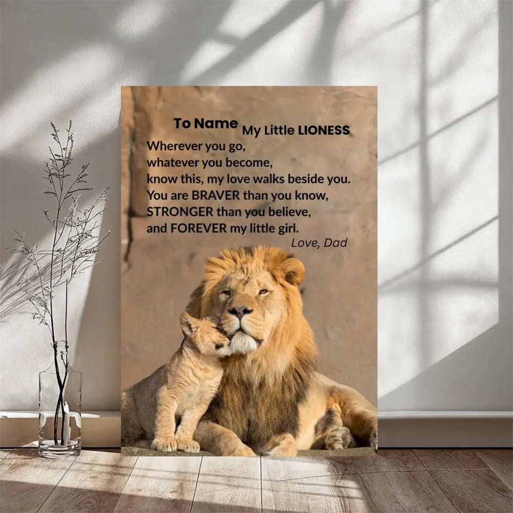 A personalized canvas print featuring a photo of a lion and cub with a poem titled 'To Name My Little LIONESS' by 'Love, Dad', displayed leaning against a wall in a room setting.