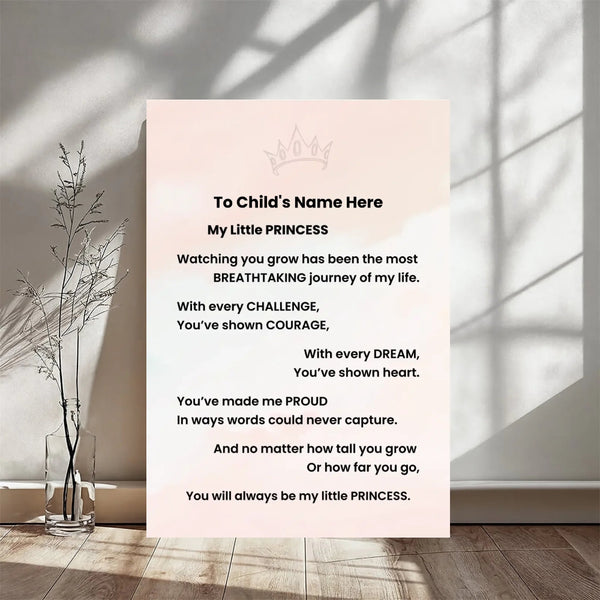 A personalized children's wall print with a soft blush pink background and black text, displayed in a styled room setting with a glass vase of dried stems on a wooden floor.