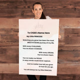 A woman holding a large personalized baby shower sign with a princess-themed poem, set against a rustic wooden wall background.