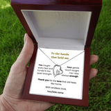 Necklace with heart pendant in a wooden box held by a hand on grass