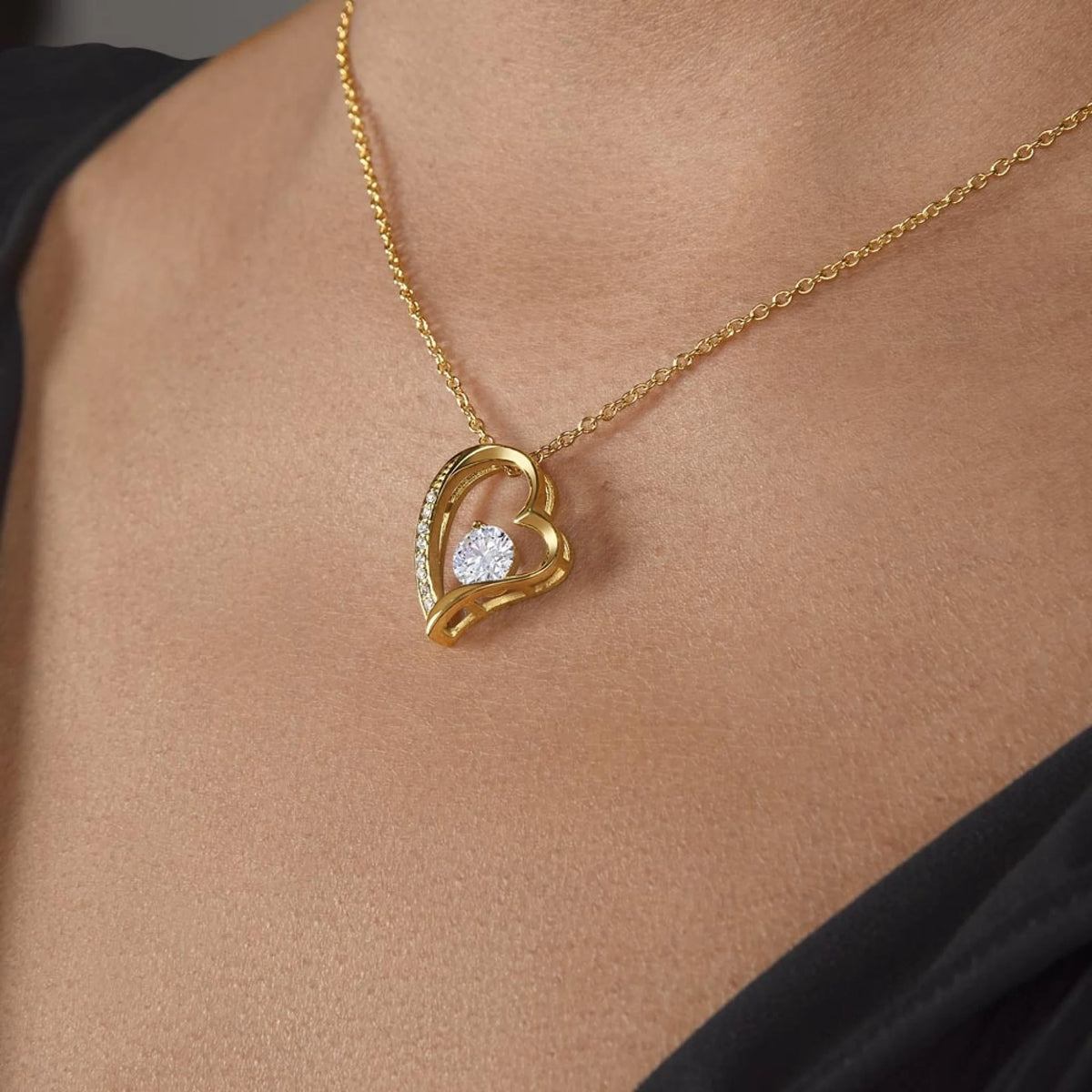 Gold heart-shaped necklace with a diamond pendant on a person's neck.