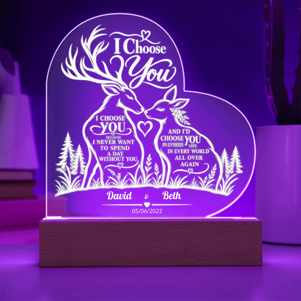 Personalized acrylic LED night light on a wooden base, featuring laser-engraved deer, trees, and romantic text, glowing with purple light in a room setting.