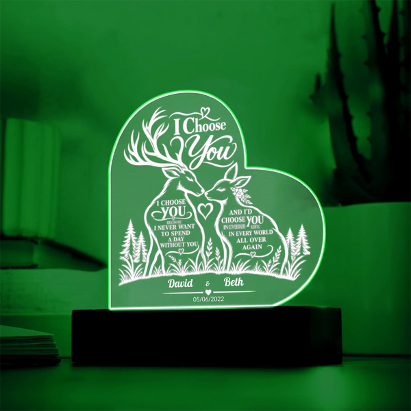 A heart-shaped LED acrylic night light glowing green, featuring a deer and forest design with personalized text 'I Choose You' and names David & Beth on a black base.