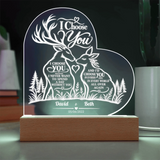 Personalized acrylic LED night light shaped like a heart, featuring a deer and forest design with the text 'I Choose You' and custom names 'David & Beth' on a wooden base.