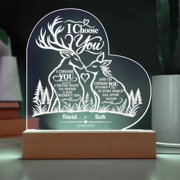 Personalized acrylic LED night light shaped like a heart, featuring a deer and forest design with the text 'I Choose You' and custom names 'David & Beth' on a wooden base.