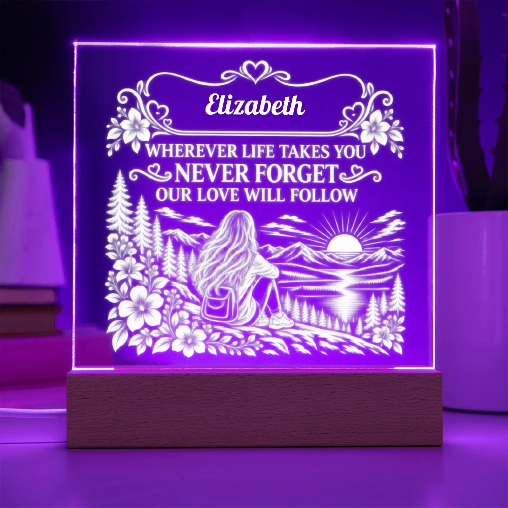 A square acrylic LED night light on a wooden base, glowing with purple light and featuring a custom engraved design with the name 'Elizabeth' and a scenic landscape illustration.