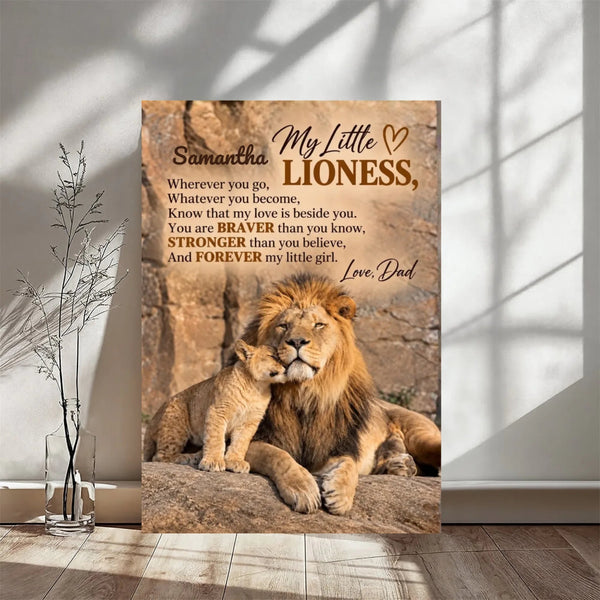 A vertical printed poster or canvas leaning against a wall in a styled interior. The artwork shows a lion and cub on a rock with memorial-style text reading 'akhrams My Little LIONESS,' and 'Love, Dad.