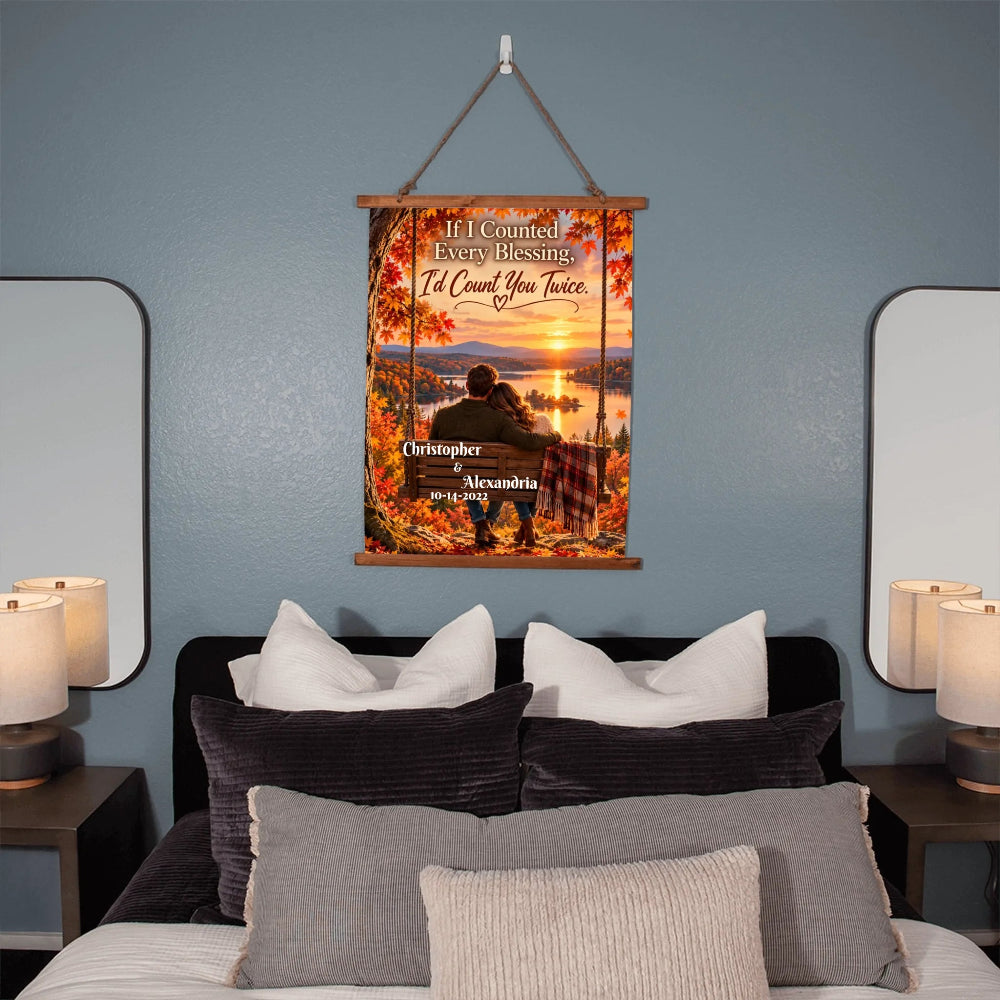 A personalized hanging wall poster with a fall sunset scene and a swing seat, displayed on a blue-gray bedroom wall above a bed with pillows and bedside lamps.