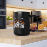 Black mug with Halloween-themed design featuring ghosts and text on a kitchen counter.