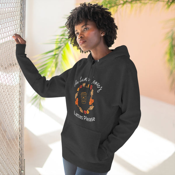 Woman wearing a black hoodie with a coffee-themed design, standing indoors with plants in the background.