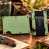 A personalized olive green metal card holder wallet shown from both sides on a rustic wooden table. One side features a black elastic money clip with a custom engraving reading 'I'M SO GRATEFUL YOU'RE MY DAD', and the other side has a printed message of gratitude.