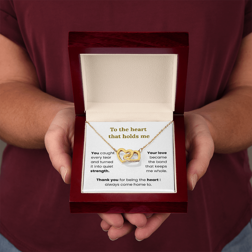 woman holding yellow gold interlocking heart necklace in lux box