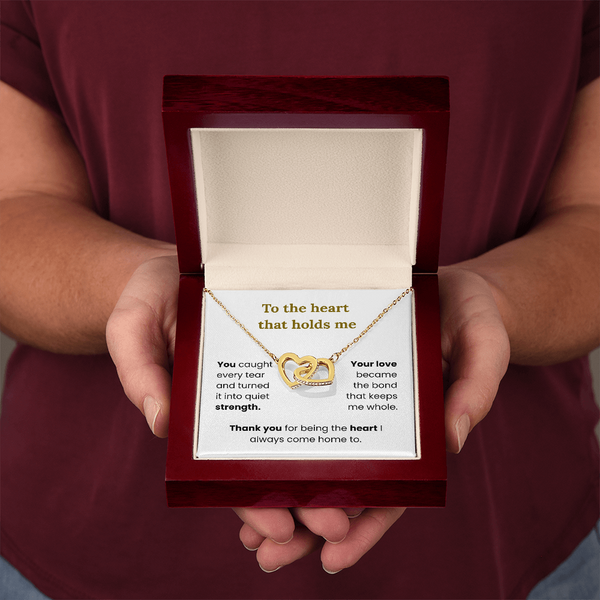 woman holding yellow gold interlocking heart necklace in lux box