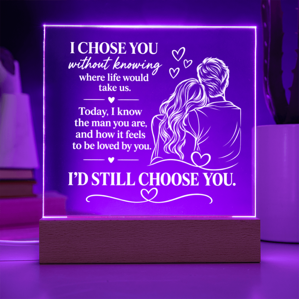 A rectangular acrylic LED lamp glowing with purple light on a wooden base, featuring white engraved text and an illustration of a couple with hearts. The message reads, 'I CHOSE YOU without knowing where life would take us.