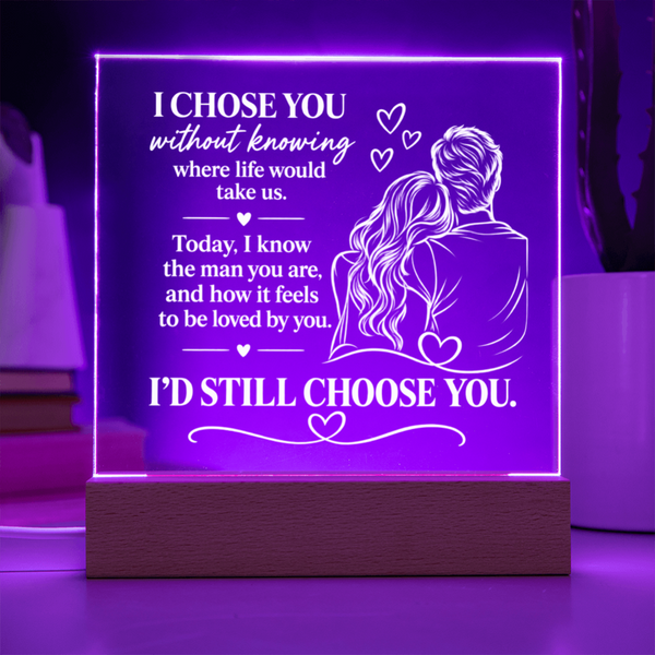 A rectangular acrylic LED lamp glowing with purple light on a wooden base, featuring white engraved text and an illustration of a couple with hearts. The message reads, 'I CHOSE YOU without knowing where life would take us.