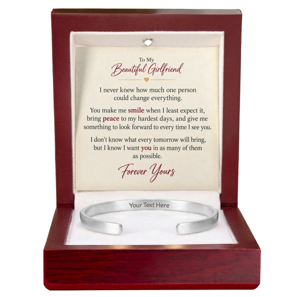A silver open cuff bracelet displayed inside a dark reddish-brown wooden gift box with a printed message card. The card reads 'To My Beautiful Girlfriend' and includes a sentimental poem, with the bottom text area labeled 'Your Text Here'.