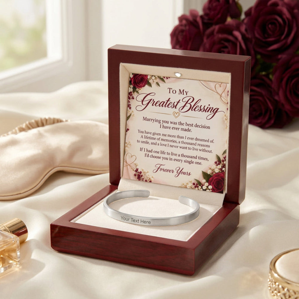 A personalized silver cuff bracelet presented in an open dark wood gift box with a floral message card. The card reads 'To My Greatest Blessing' and includes a romantic poem for marriage, with rose and floral illustrations.