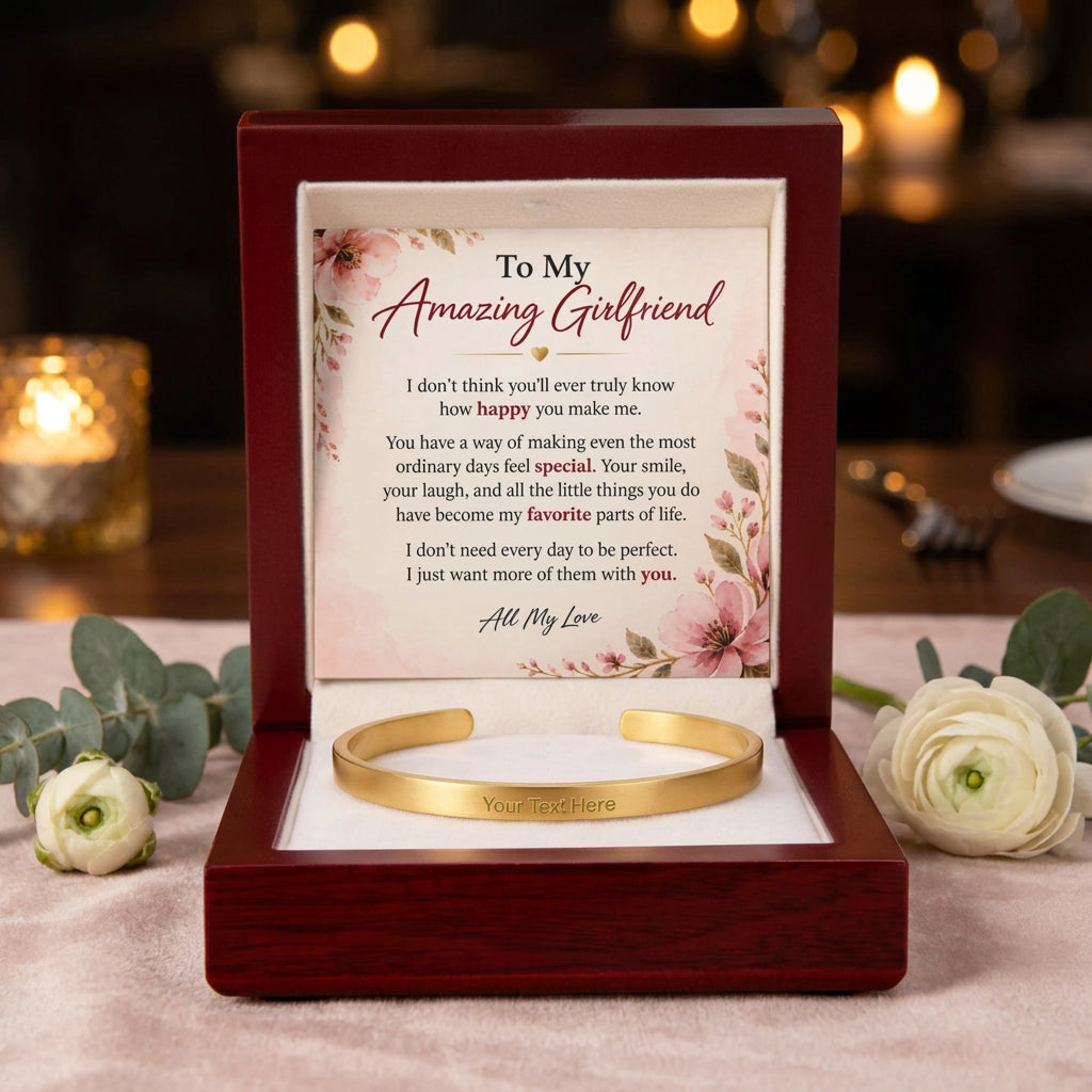 A gold heart-shaped cuff bracelet presented in a dark red wooden gift box with a floral message card that reads 'To My Amazing Girlfriend' and includes a customizable text placeholder on the bracelet.