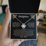 A hand holds an open black jewelry gift box containing a silver chain necklace with a clear crystal pendant, displayed on a black printed message card with German text.
