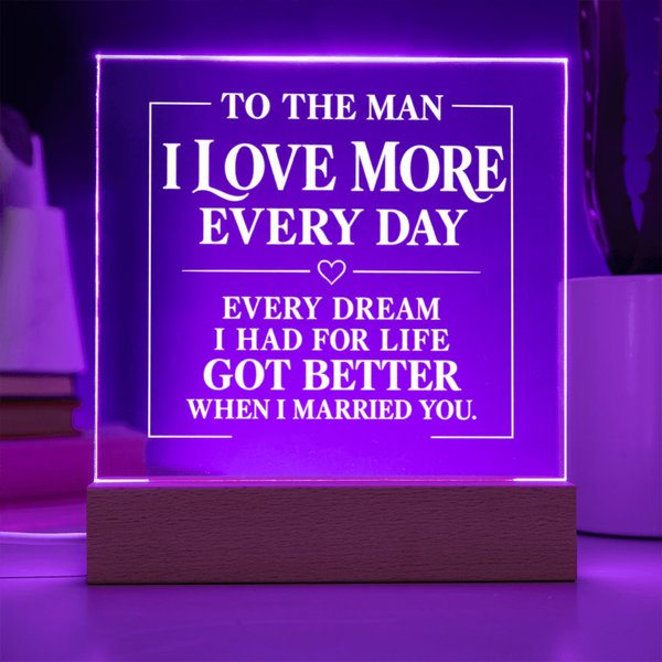 A rectangular LED acrylic night light on a wooden base, glowing with purple light and featuring white printed romantic text that reads, 'TO THE MAN I LOVE MORE EVERY DAY EVERY DREAM I HAD FOR LIFE GOT BETTER WHEN I MARRIED YOU.'.