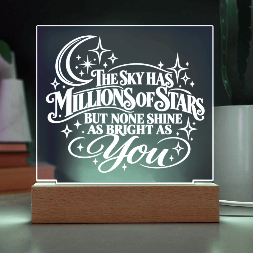 A wooden LED acrylic night light displaying the quote 'THE SKY HAS MILLIONS OF STARS BUT NONE SHINE AS BRIGHT AS YOU' in white script, set against a dark background with a warm glow.
