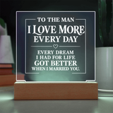 A rectangular acrylic LED night light with a wooden base, displaying a romantic message for a husband. The text reads 'TO THE MAN I LOVE MORE EVERY DAY' and 'EVERY DREAM I HAD FOR LIFE GOT BETTER WHEN I MARRIED YOU.
