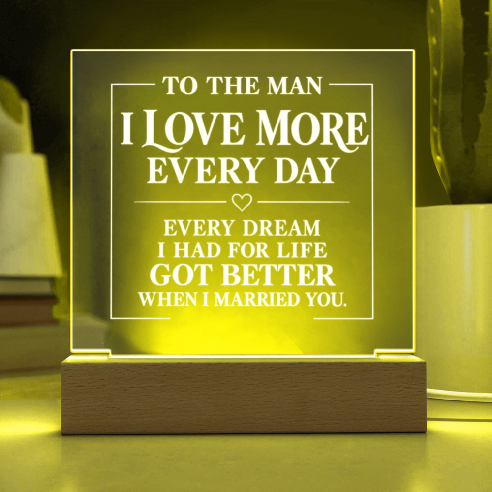 A rectangular acrylic LED night light with engraved white text on a wooden base, glowing with a warm yellow light in a home setting.