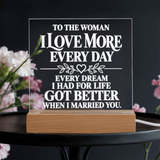 A rectangular acrylic LED light sign with white text reading 'TO THE WOMAN I LOVE MORE EVERY DAY.