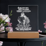 A rectangular acrylic LED light box with a wooden base, featuring a romantic quote and an illustration of a couple kissing. The text reads, '4 BILLION MEN.