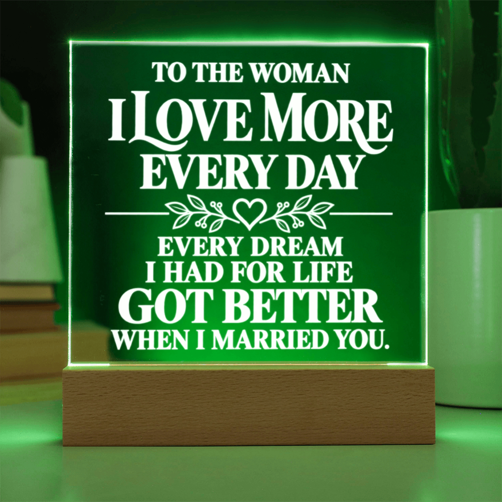 A rectangular acrylic LED night light on a wooden base, glowing with a green light and featuring white text that reads, 'TO THE WOMAN I LOVE MORE EVERY DAY EVERY DREAM I HAD FOR LIFE GOT BETTER WHEN I MARRIED YOU.'.