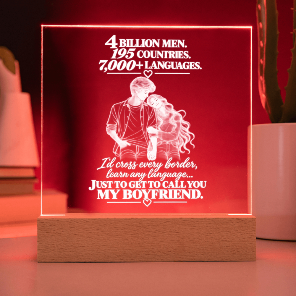 A square acrylic LED lamp on a wooden base, glowing with a warm red light. The front features a white laser-engraved illustration of a couple and romantic text about calling your boyfriend.
