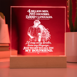 A square acrylic LED lamp on a wooden base, glowing with a warm red light. The front features a white laser-engraved illustration of a couple and romantic text about calling your boyfriend.