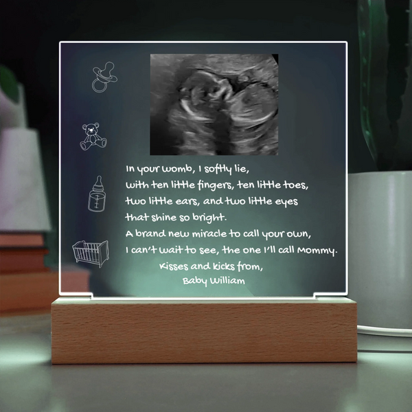 Framed ultrasound photo with baby milestone message on a stand
