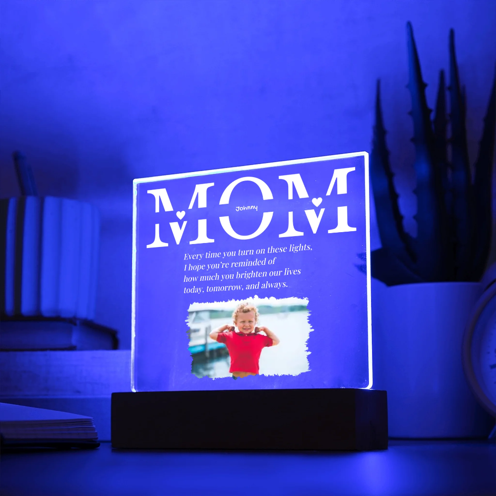 Acrylic plaque with 'MOM' and a photo of a child on a stand, illuminated by blue light.