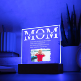 Acrylic plaque with 'MOM' and a photo of a child on a stand, illuminated by blue light.
