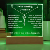 Decorative sign with engraved message for a graduate on a wooden stand with green glowing border.