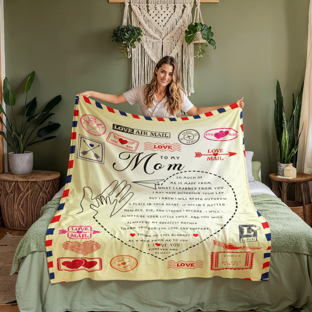 Woman holding a decorative blanket with 'Love to My Mom' text in a cozy room.