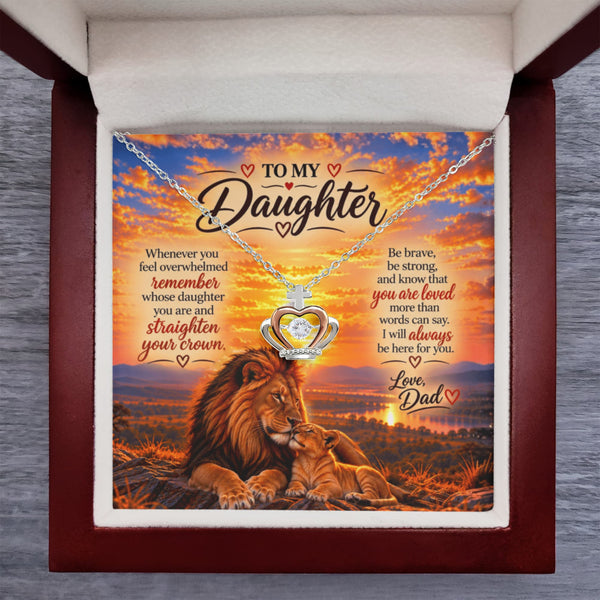 A heart-shaped silver pendant necklace displayed on a printed gift card inside a dark wood presentation box. The card reads 'TO MY Daughter' and features an illustration of a lion and cub under a sunset sky, with supportive text.