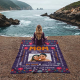 Person sitting on a blanket with personalized message by the ocean