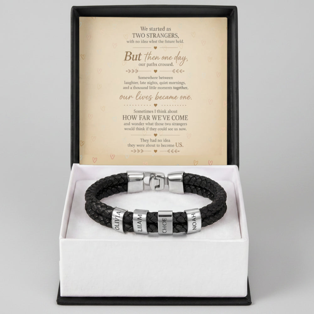 A black braided cord bracelet with silver metal beads and nameplates spelling 'SUPRA', 'MUNDI', and 'DIVINA', presented in an open white gift box with a black base. A printed message card is displayed behind the bracelet.