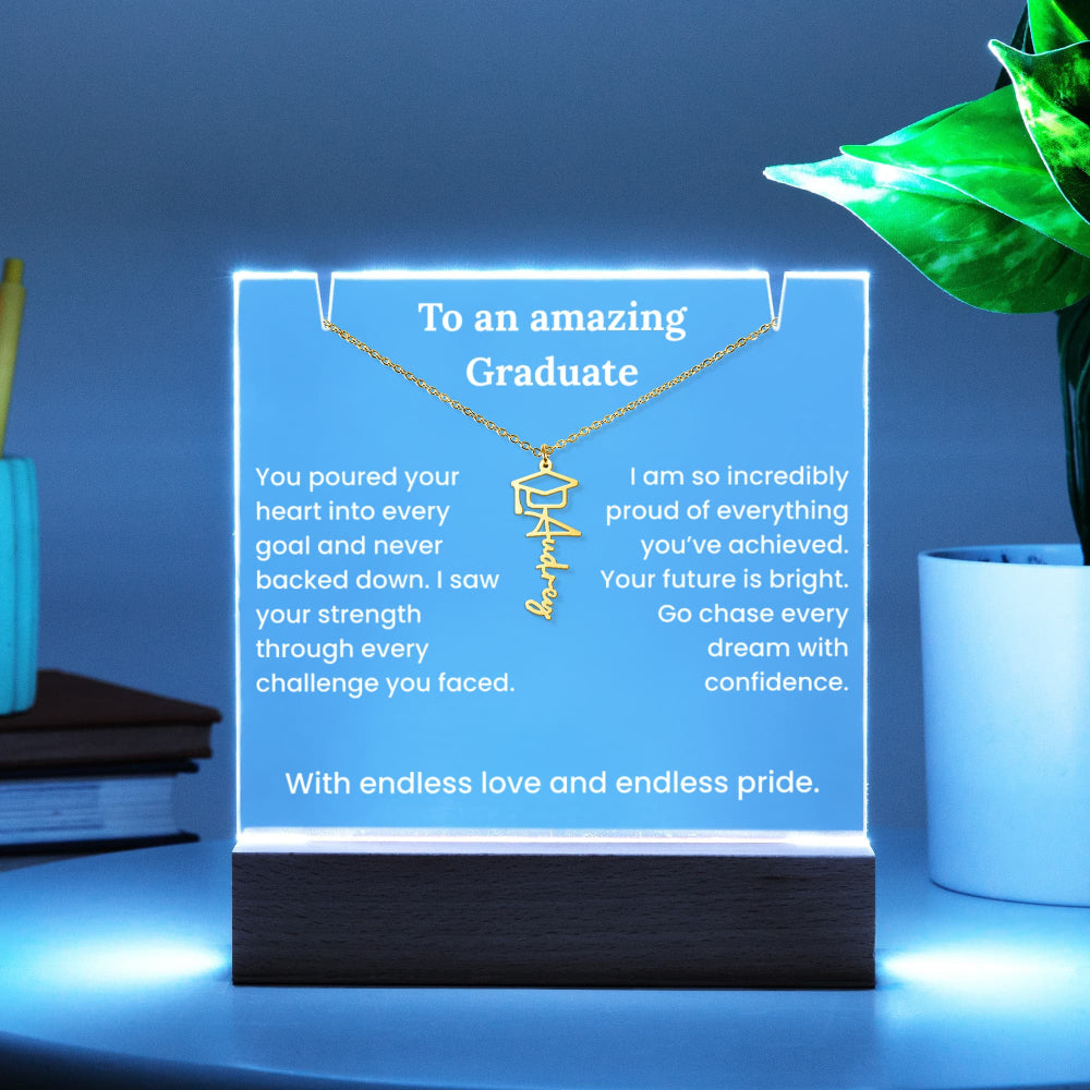 Necklace with engraved message on a glowing stand, placed on a surface with a plant and books in the background.
