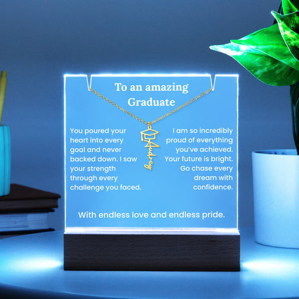 Necklace with engraved message on a glowing stand, placed on a surface with a plant and books in the background.