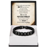 A black braided cord bracelet with rectangular nameplates spelling out 'JOHN', 'WORLD', 'FAMILY', 'LOVE', 'HONOR', 'GRACE', 'GOD', and 'TIME' is displayed inside an open gift box with a sentimental message card for Dad.