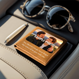 A personalized leather wallet with a photo of a father and son and the text 'SAMPLE PHOTO' and 'Son, wherever you go, never forget that a piece of me goes with you.' styled on a car seat next to sunglasses, a pen, and a notebook.