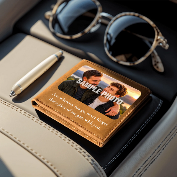 A personalized leather wallet with a photo of a father and son and the text 'SAMPLE PHOTO' and 'Son, wherever you go, never forget that a piece of me goes with you.' styled on a car seat next to sunglasses, a pen, and a notebook.